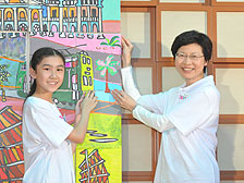 共建香港: 政務司司長林鄭月娥與小朋友把他們的作品拼貼成啟動禮背景板上兩幅大型城市景觀圖。